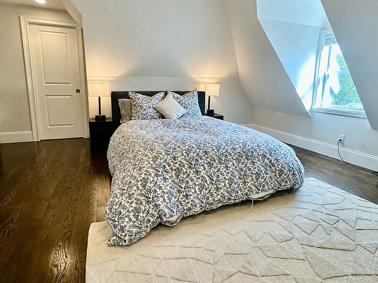 Spacious primary bedroom with hardwood floors, peaceful natural light, and tree-top views.