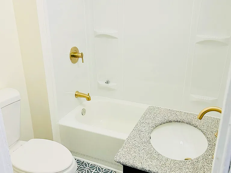 Newly renovated bathroom with tub and granite countertop.