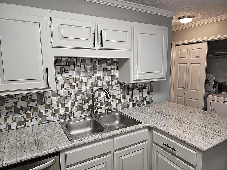 Stainless steel sink & granite counter tops in kitchen.