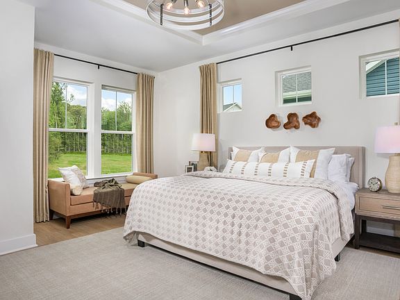 Owner s suite with tray ceiling and multiple windows at a DRB Homes Palm model home at the Chase Oak