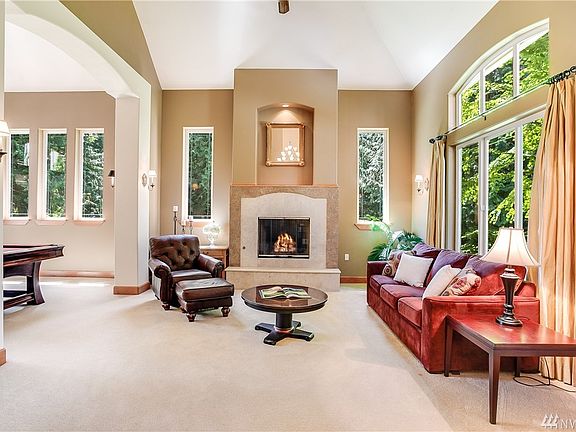 A soaring coved ceiling, travertine accented fireplace with a raised hearth and gas ignitor plus jumbo windows highlight the formal living room.