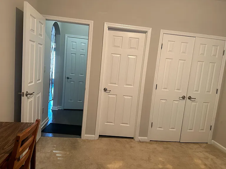 Carpeted interior hallway with multiple doors, including a double-door closet, offering convenient access and storage.