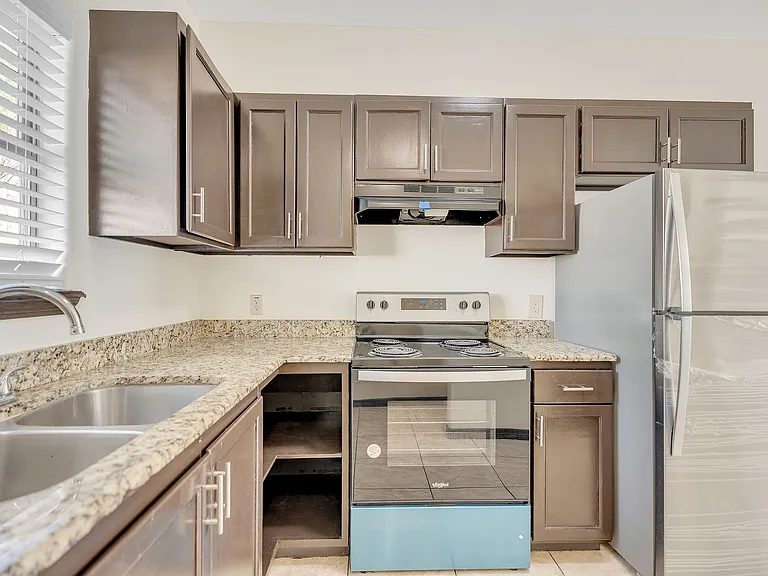 Contemporary kitchen in La Joya Apartments showcasing stainless steel appliances and polished granite countertops