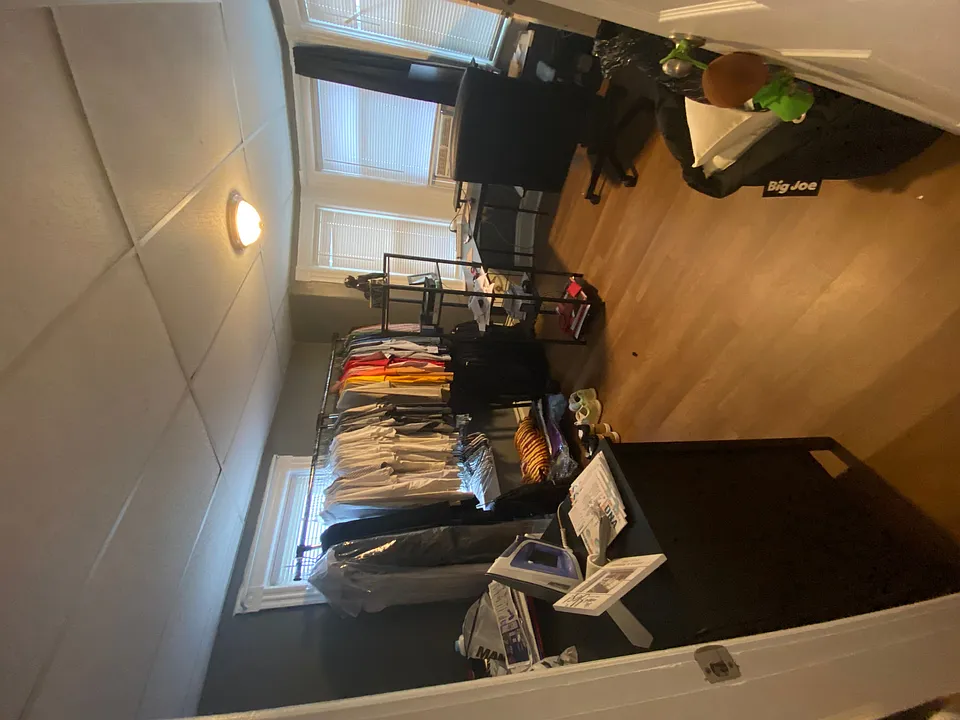 This room includes the dresser and a U shaped work desk and chair, and clothing rack.