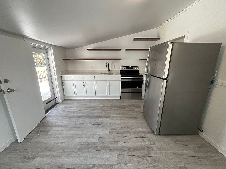 Updated kitchen with a single sink, quartz countertop, electric oven, and refrigerator
