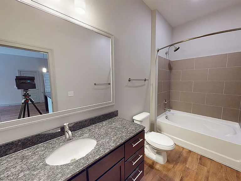 Apartment bathroom with large soaking tub and wood-style flooring.