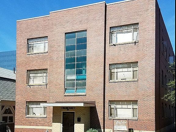 Elegant brick apartment building with large windows and a well-maintained lawn.