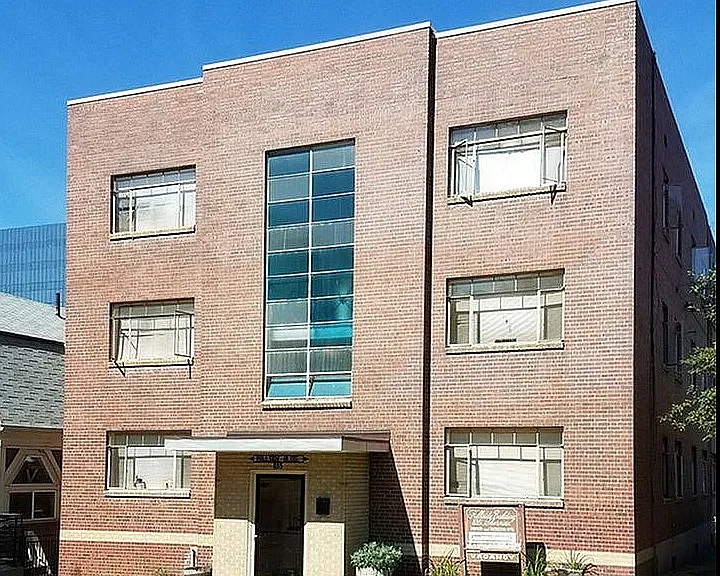 Elegant brick apartment building with large windows and a well-maintained lawn.