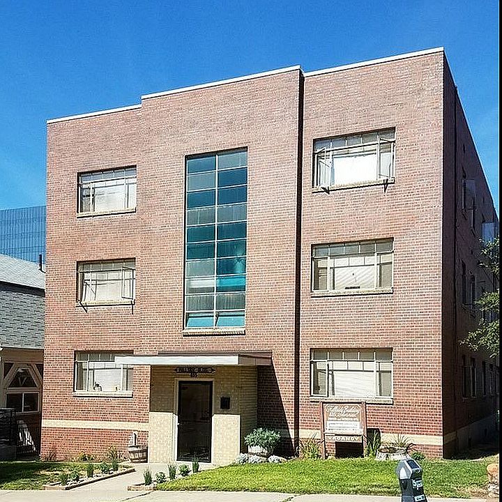 Elegant brick apartment building with large windows and a well-maintained lawn.