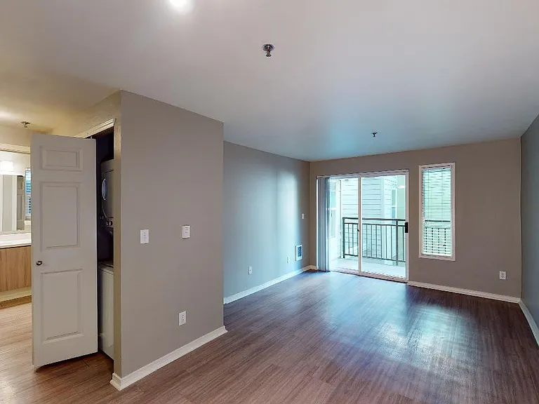 Apartment living room with wood-style flooring and patio or balcony in select homes.