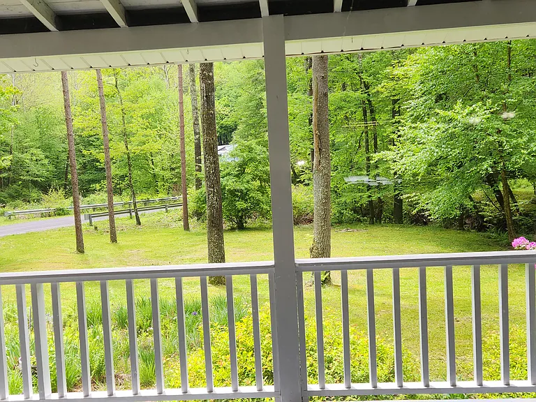view out of large window of living room looking over porch into front yard