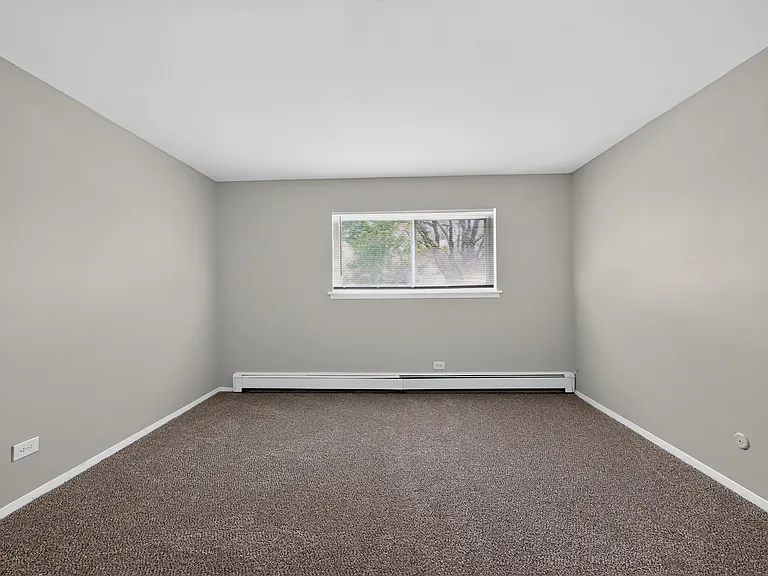 Enjoy a bright, open bedroom featuring plush carpeting and natural light at Renaissance at Carol Stream in Carol Stream, IL.