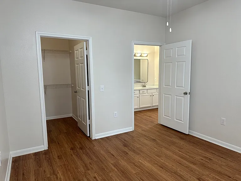 Inviting bedroom with elegant wood-style floors, spacious closet, and ensuite bathroom, ideal for modern living. Inviting bedroom with elegant wood-style floors, spacious closet, and ensuite bathroom, ideal for modern living.