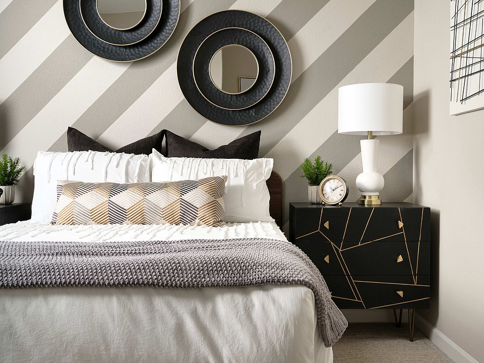 The image depicts a modern and stylish bedroom interior, featuring a large bed with a gray and white