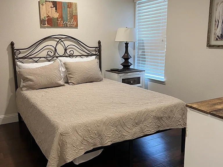 Comfortable second bedroom featuring hardwood floors, ceiling fan, and stylish furnishings.