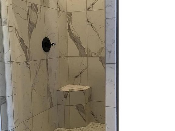 The master bath has stunning marbled tile throughout. Pictured here is the large walk-in shower in the master bath.