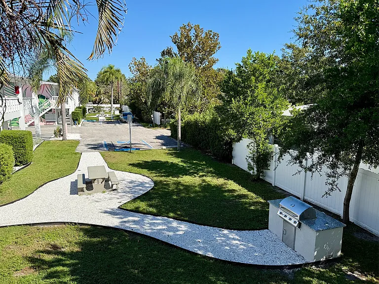 Serene outdoor space featuring a picnic area, lush green lawn, and modern barbecue grill, perfect for entertaining and relaxation.