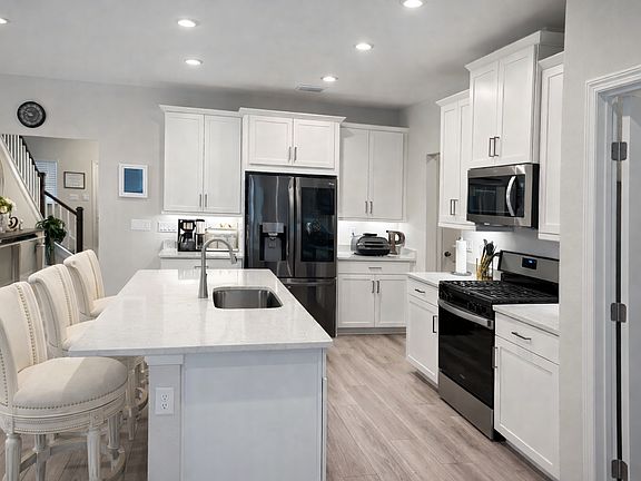 Bright kitchen featuring white cabinetry, stainless steel appliances, and ample counter space.