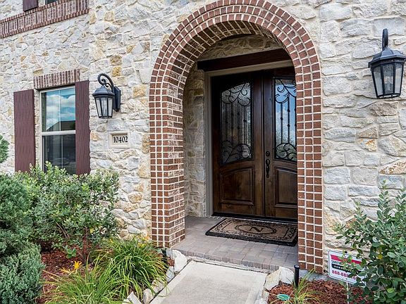Stucco, stone and brick exterior leads up to these beautiful double iron & wood doors!