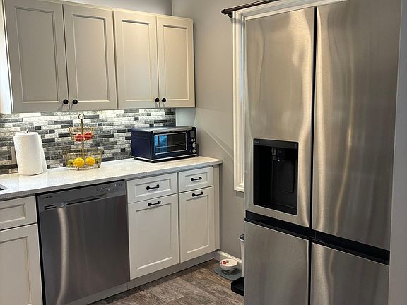 Kitchen with backsplash, dishwasher, and tile floors