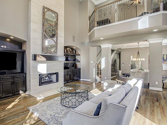 This view of the living room shows the elegant built-in bookcases with display lighting, and the balcony off the upstairs master suite. This home is truly remarkable!