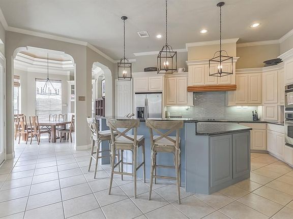 Chef's kitchen boasts an island with breakfast bar, stainless appliances and designer lighting.