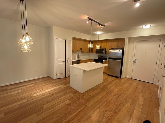 Large open kitchen with need light fixtures, stainless steel appliances, and island