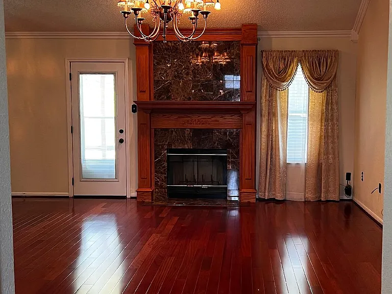 Living room - Featuring a marble surround fireplace & chandelier.