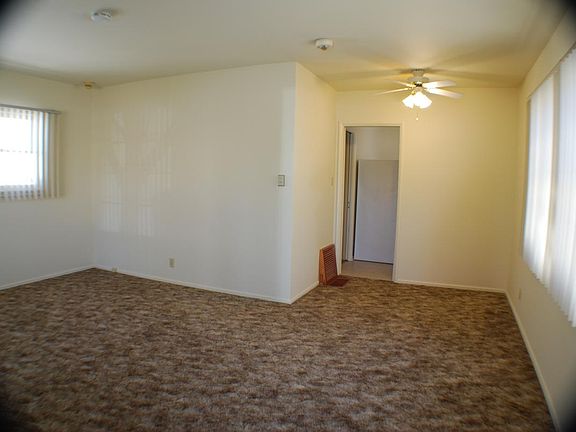 Entering living room from front door, leading to dining area with ceiling light/fan, then into the kitchen.