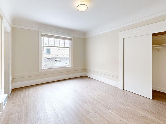 Sunlit room with a large window, wood-like flooring, and closet