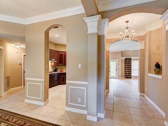 View from entry towards the formal dining (left) and kitchen and den, high ceiling, crowning moldings, tile flooring