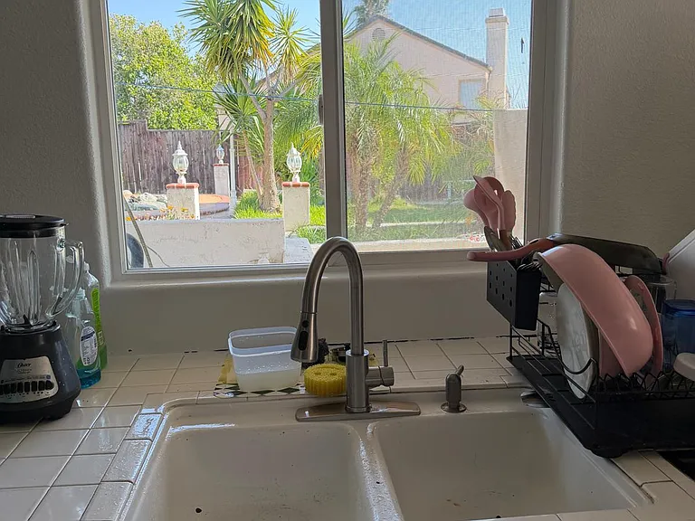 Kitchen sink area with a large window overlooking the yard, plus ample counter space for prep and dishwashing.