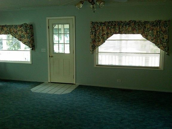 The living room is carpeted and overlooks the large front porch and yard.