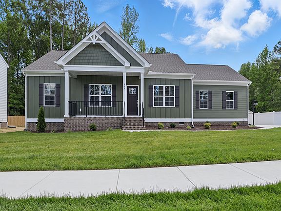 Single-story Poplar Village green house with white trim, front porch, and manicured lawn on a sunny
