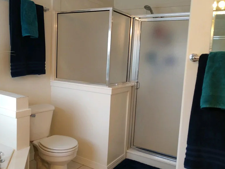 Large shower with two shower heads and bench in master bath.