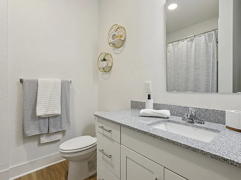 Elegant bathroom featuring sleek granite countertop, modern fixtures, stylish wall decor, and soft lighting.
