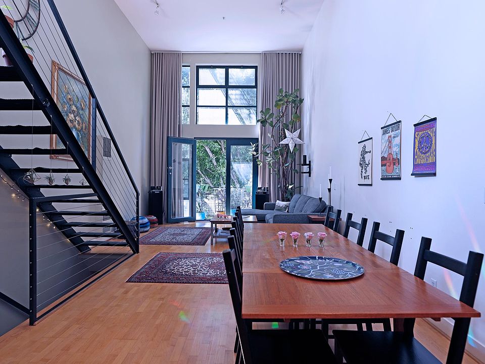 Dining table, living room, Juliette balcony. 16.5 ft ceilings with huge ripple curtains. Take the stairs up to lofted bedroom or down to the bedroom and garage downstairs on the ground floor.