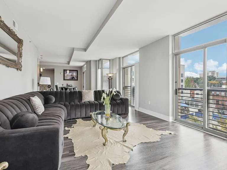 Spacious living room with floor-to-ceiling windows, modern flooring, and skyline views.
