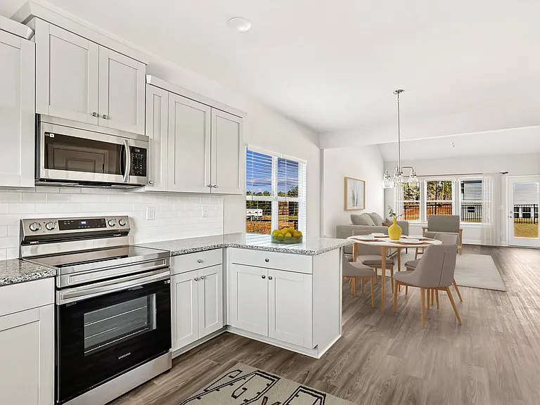 Full view of the kitchen and adjoining dining area, featuring a table and chairs for comfortable dining.