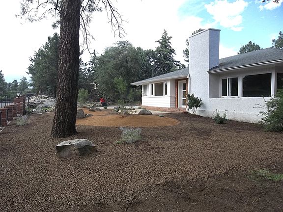 Front yard features large Ponderosa pine. Iron fence with ga
