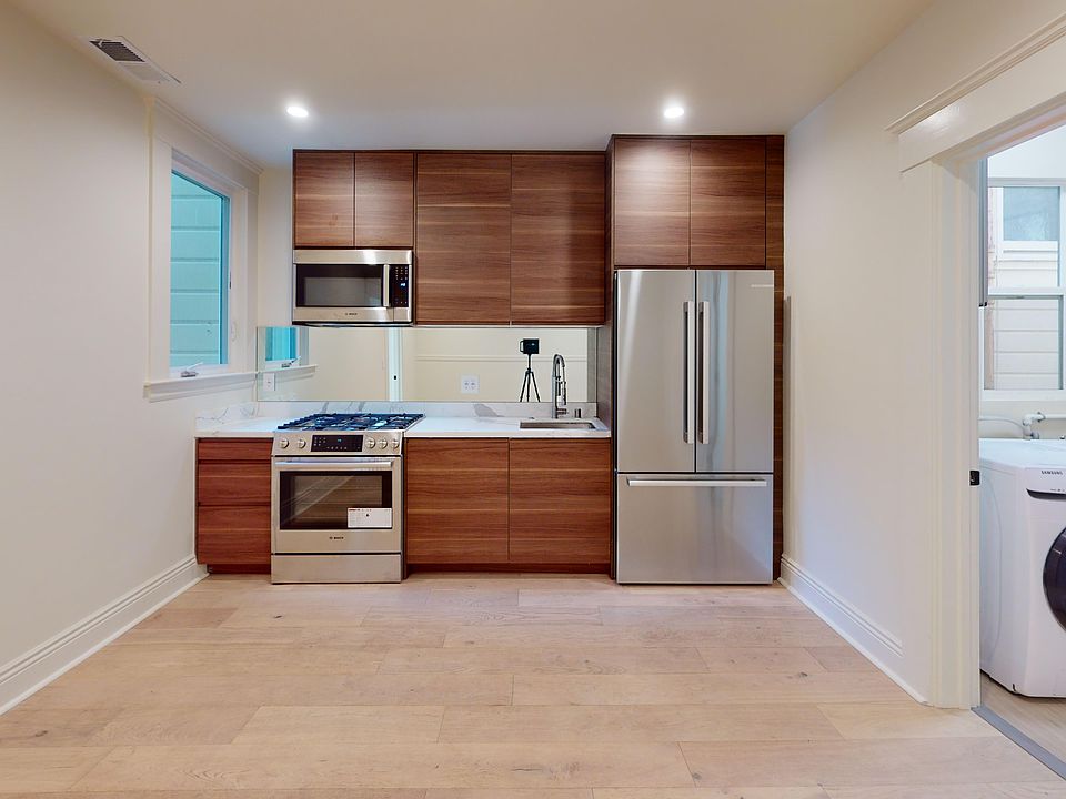 Kitchen with multiple cabinets, refrigerator, stove, microwave oven, sink, and an in-unit washer