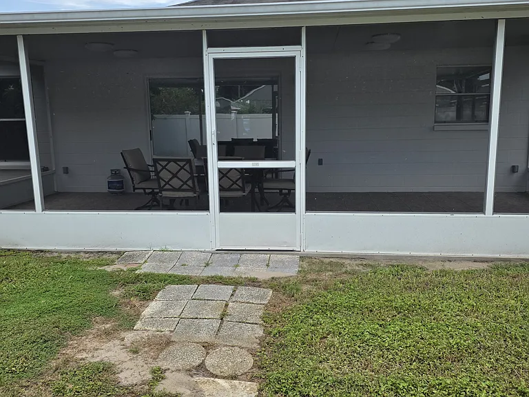 backyard picture showing font of screened in patio