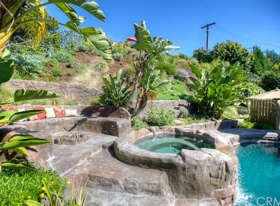 Raised spa with waterfall and built-in seating area surrounding the fire pit