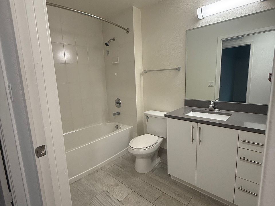 Modern bathroom featuring sleek flooring, spacious vanity with ample storage, and a contemporary shower design.