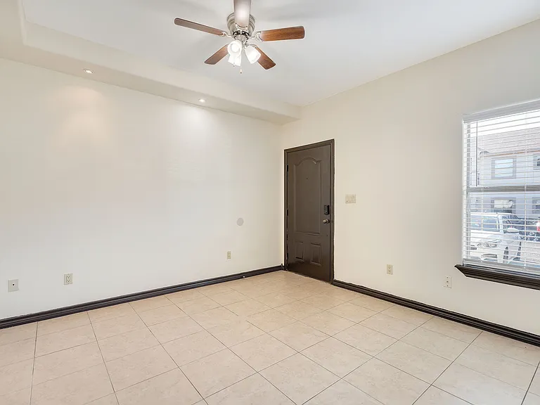 Elegant empty room with tile flooring and a ceiling fan, showcasing the refined interior of Merida Vista Apartments, Laredo, Texas