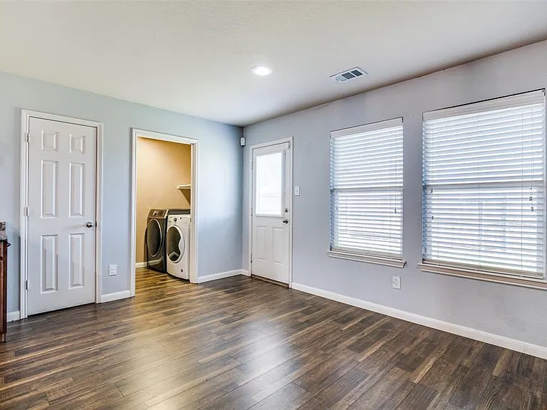 Unfurnished bedroom with a spacious closet, washing machine and dryer, dark hardwood / wood-style flooring, and multiple windows