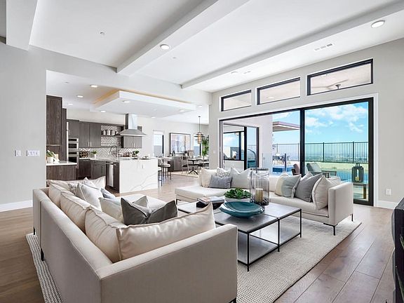 A spacious and modern living room with a large sectional sofa, a glass-topped coffee table, and a ki