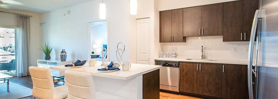 Kitchens feature European espresso custom cabinets with quartz countertops, stainless steel appliances, white tile backsplash, and hard surface flooring