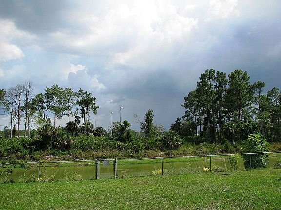 View of back yard with wide canal beyond fence 
