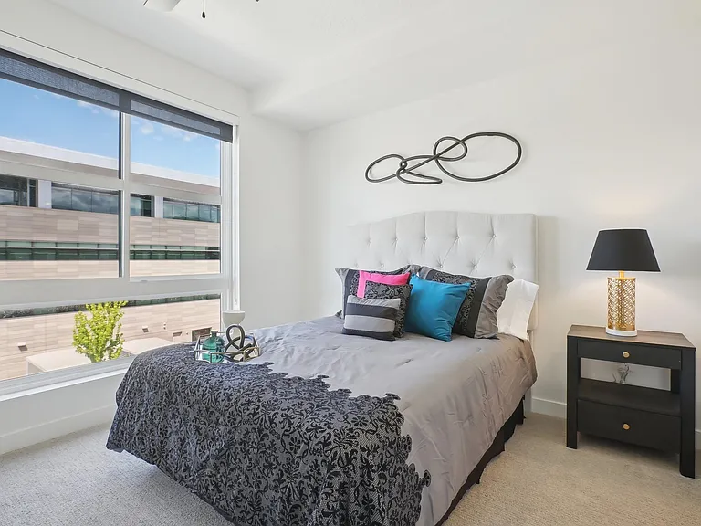 Liberty Duet Apartments, Salt Lake City, Utah; A bedroom with a large bed and a window overlooking a building.